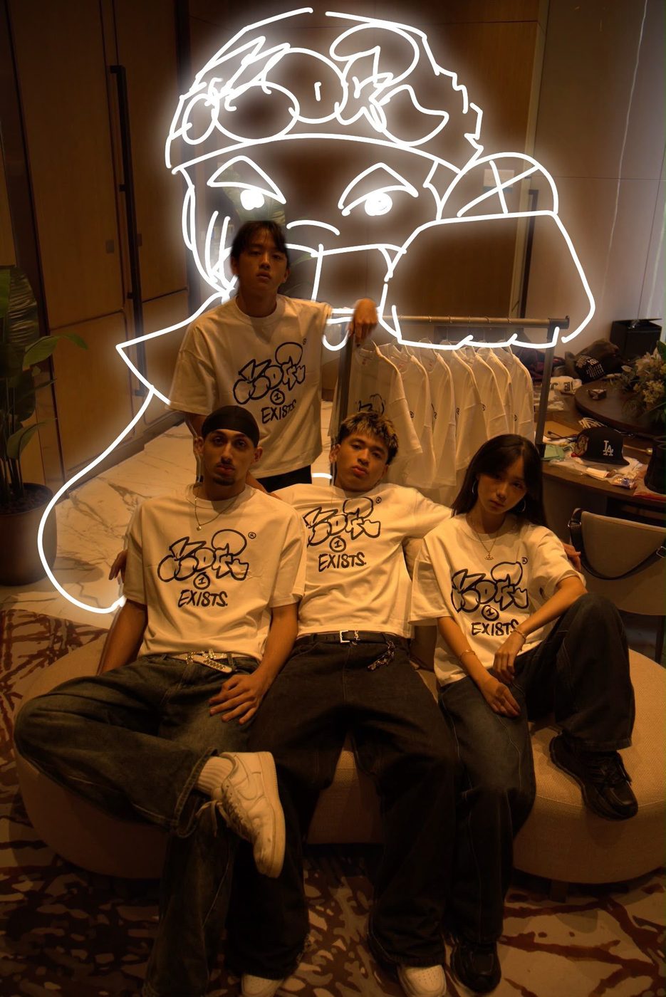 Four people in Drop 0 tees, the MOGI face drawn over the photograph