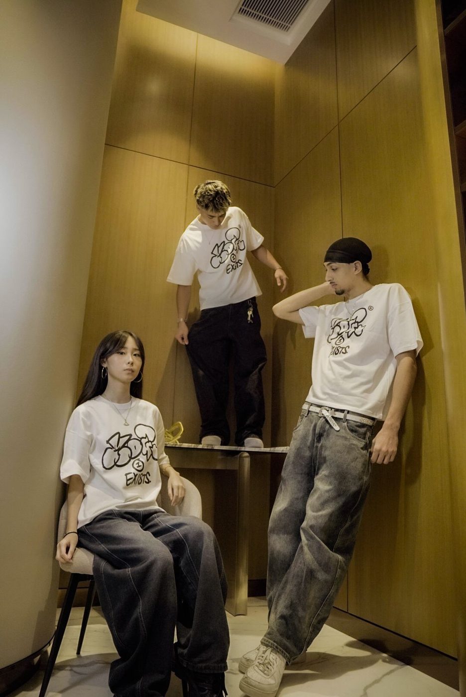 Three people in Drop 0 tees in a wood-panelled corner